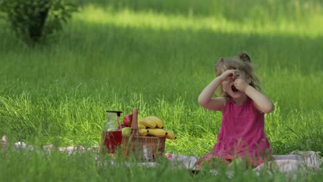 Wochenende-Beim-Picknick.-Schönes-Kaukasisches-Kindermädchen-Auf-Der-Wiese-Mit-Grünem-Gras,-Das-Fröhlich-Isst,-Kirsche