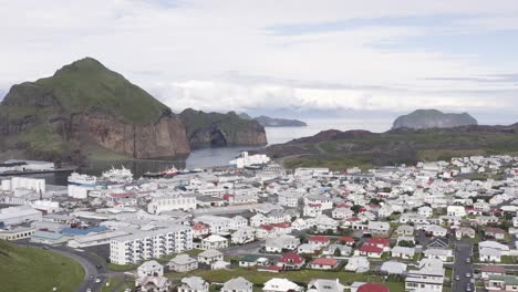 descending aerial over small town of heimaey with traditional white buildings