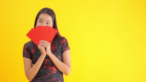 Mujer-Asiática-Con-Ropa-Tradicional-China-Celebrando-El-Año-Nuevo-Chino-Y-Cubriendo-Su-Rostro-Con-Papeles-Rojos-O-Cupones