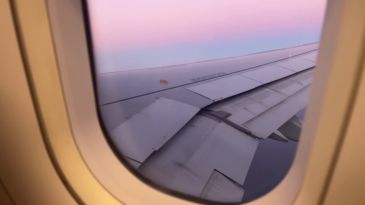 Airplane wing seen from a passenger window during sunset flight