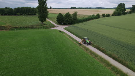 Traktor-Fährt-Rückwärts-über-Eine-Straße-In-Einer-Belgischen-Landschaft