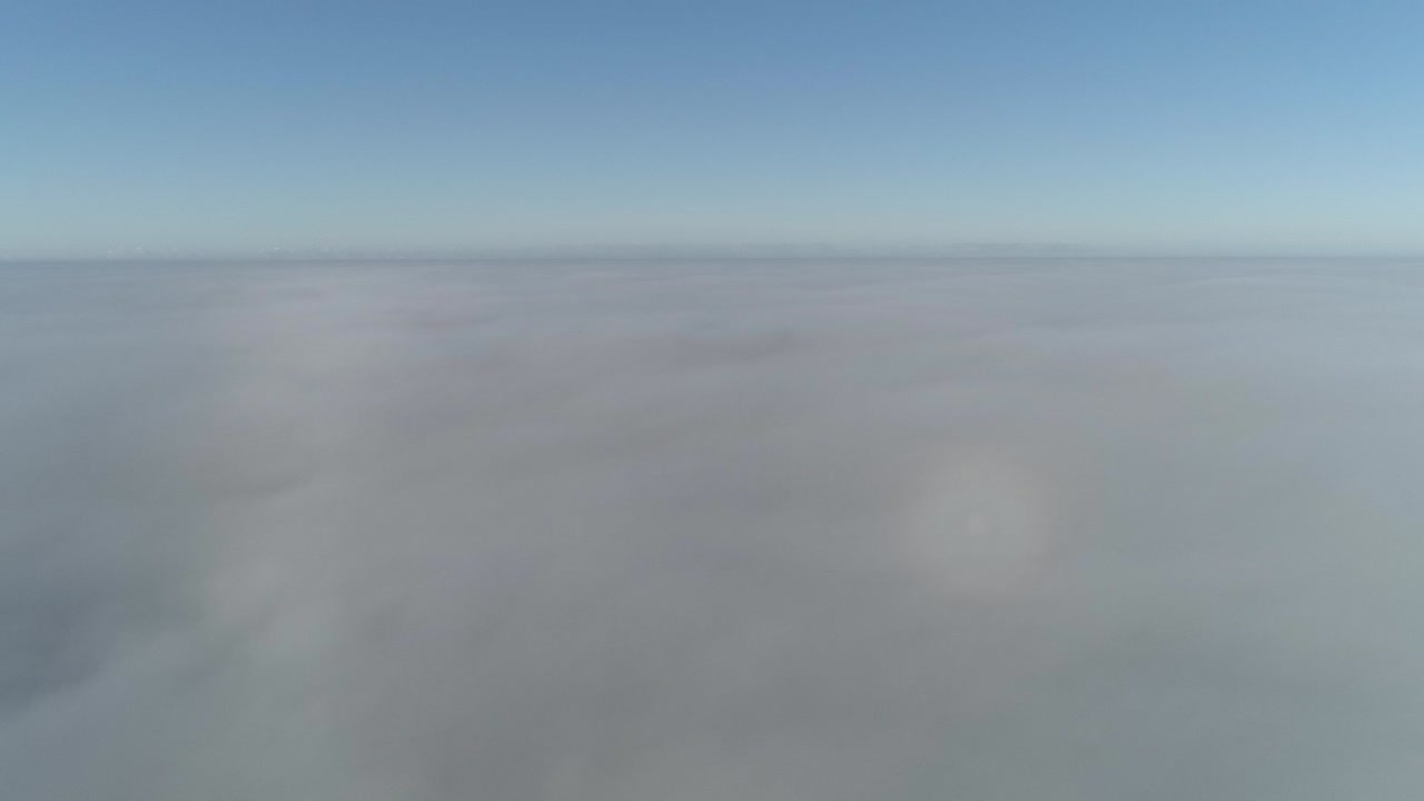 vuelo sobre nubes brumosas a la luz del sol de la mañana con poca gloria y paisaje urbano bajo las nubes