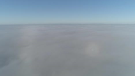 flight over misty clouds in morning sunlight with little glory and city scape under clouds