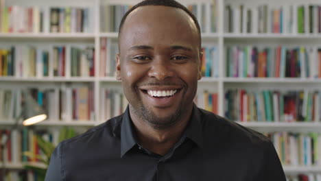 Retrato-De-Un-Joven-Afroamericano-Riéndose-Mirando-La-Cámara-De-Pie-En-La-Biblioteca