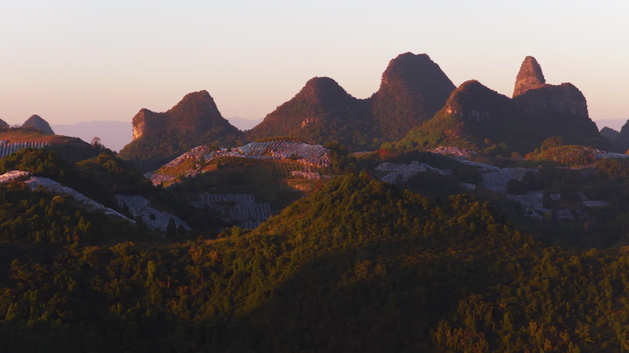 Dramatiske kalkstensklipper ved solopgang i et karstbjerglandskab i Yangshuo, Guilin, Kina. Bredt dronebillede.