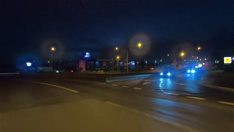 rear facing night driving point of view pov for interior car scene green screen replacement - exiting motorway and turning right at a large and busy roundabout intersection
