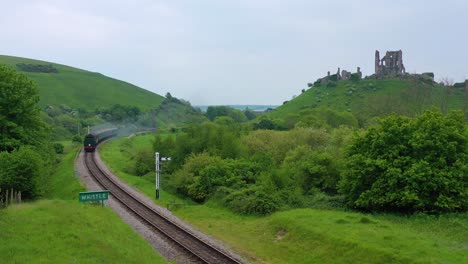 Antenne-Eines-Alten-Dampfzuges-Passiert-Die-Ruinen-Von-Corfe-Castle-Dorset-England