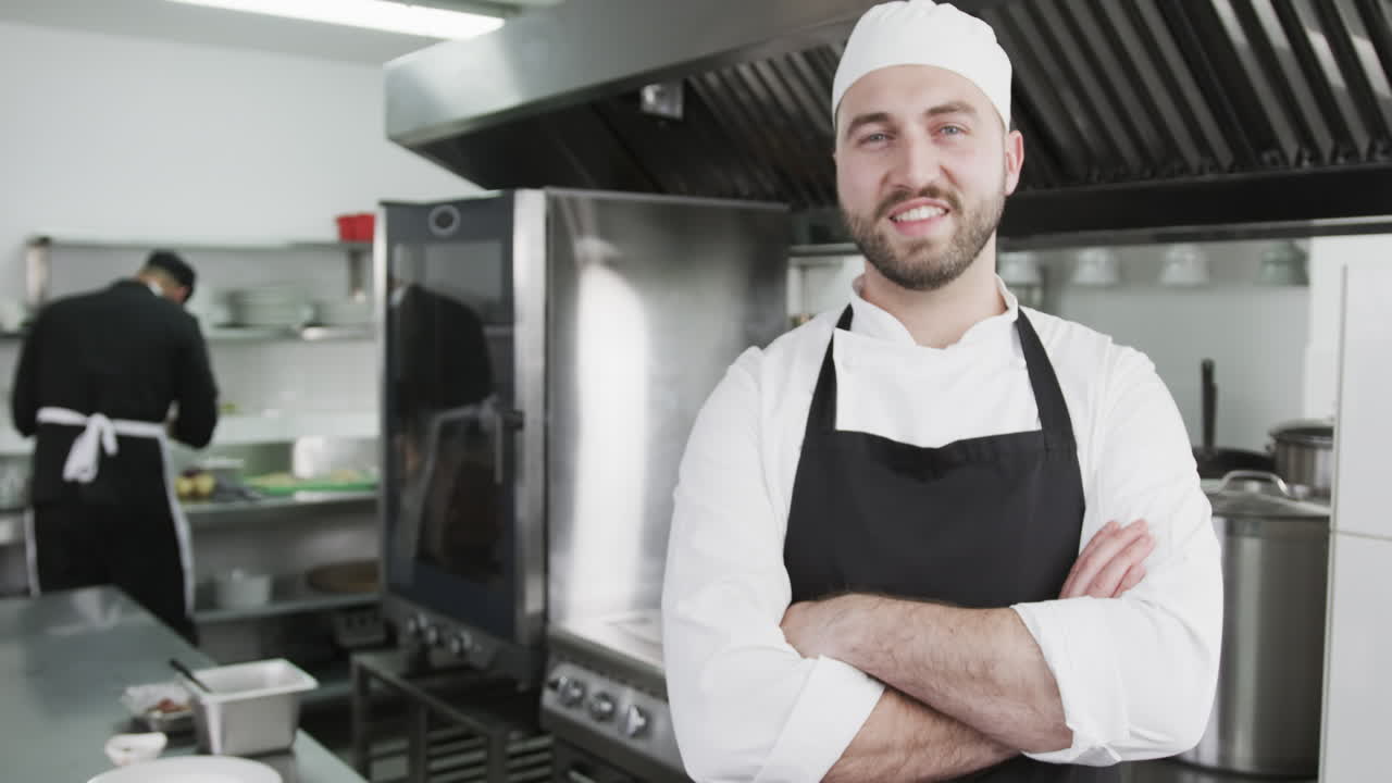 hombre caucásico chet sonriendo y con los brazos cruzados en la cocina, cámara lenta