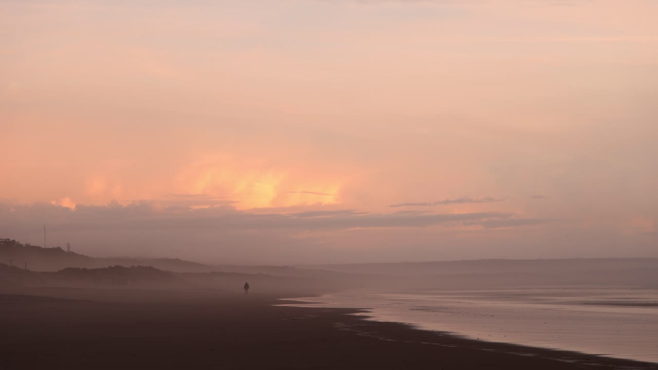 안개 속의 해변에서 하루가 끝날 무렵 평화로운 산책을 하는 남자, 다채로운 반사, 4k