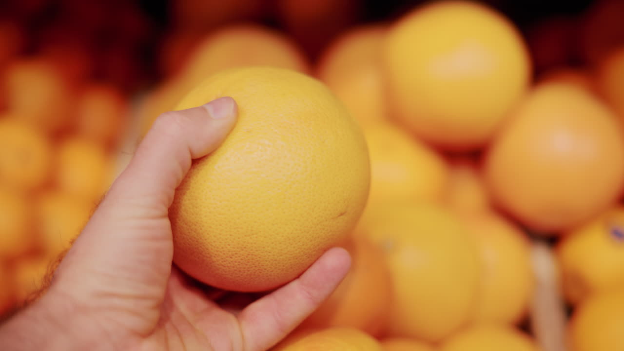 Close up of a hand holding a bright orange fruit in a market