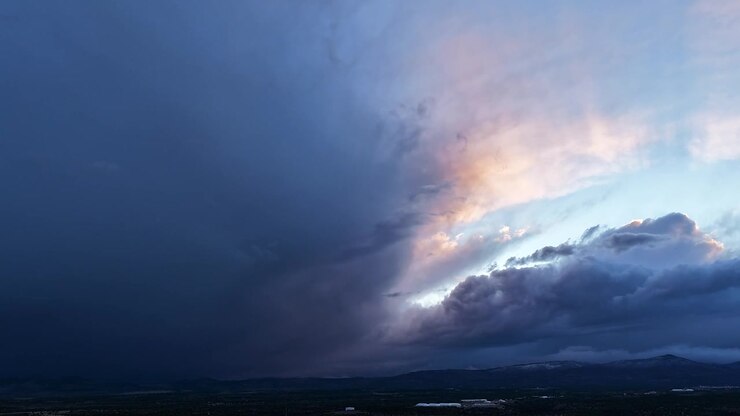 4K drone timelapse captures the moment a dark storm front engulfs the last sunset light. Dramatic atmospheric motion reveals shifting colorful clouds and heavy weather over a vast desert horizon.