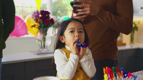 Daughter-With-Party-Blower-Celebrating-Birthday-With-Father-At-Home