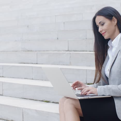 mujer sonriente usando una laptop en las escaleras