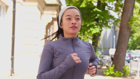 Close-Up-Of-Young-Woman-Exercising-Running-Along-Urban-Street-Wearing-Wireless-Earbuds-3