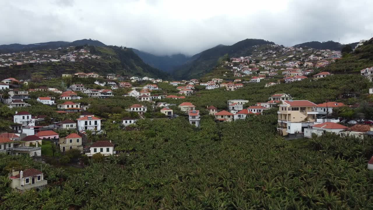 Flying toward mountains dotted with scattered houses, revealing scenic landscapes and rural charm. Captured by drone, ideal for travel and aerial content. Madeira