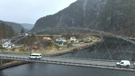 white minibus with tourists passing old steel bridge at stamneshella in early spring season, aerial