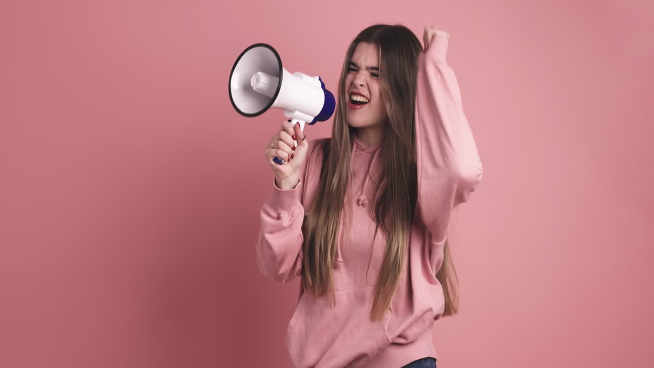 Excited young female standing and announcing into loudspeaker
