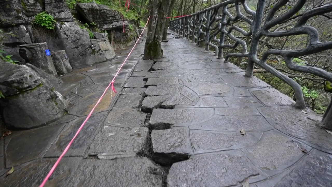 Sprekkete steinbelegg som viser jordskjelvskader på en fjellgangvei i Zhangjiajie nasjonalpark