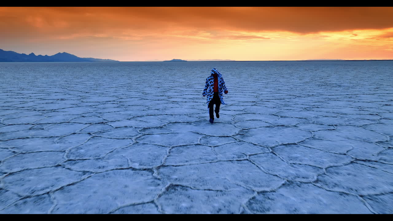 Distancing from a man walking by the Bonneville Salt Flats, Utah, USA. Stunning orange sky at sunset at backdrop