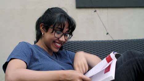 A-young-Latina-woman-laughs-while-reading-a-textbook
