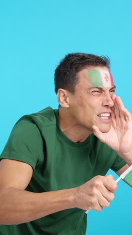 Man cheering for Mexico waving a national flag looking away