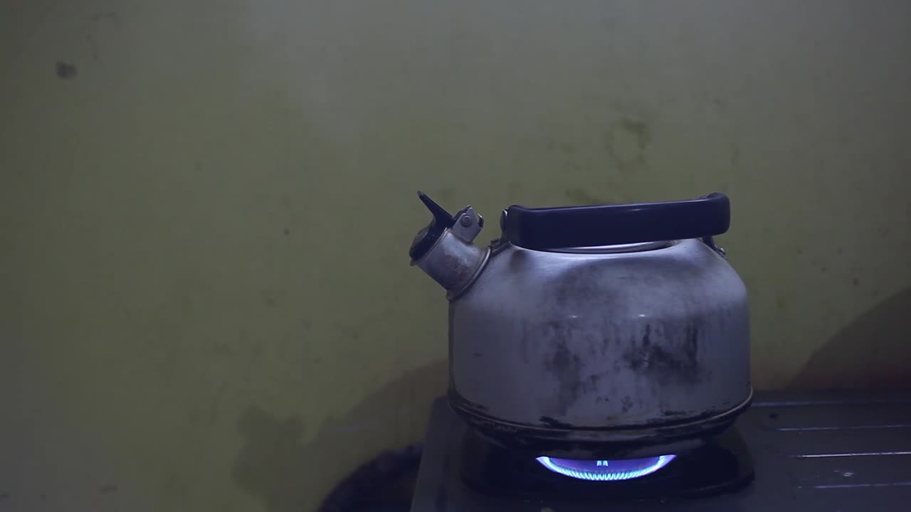 가난한 부엌의 스토브에 끓는 물을 넣은 금속색 주전자