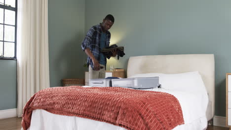 man packing suitcase in cozy bedroom, preparing for holiday travel