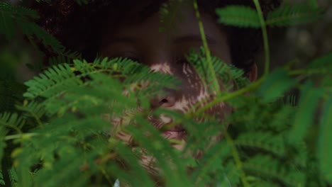 red curly hair girl in a park with leaves of a tree in the foreground