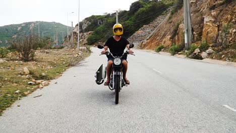 man with surfboard travels on motorbike, vietnam ninh thuan province road trip