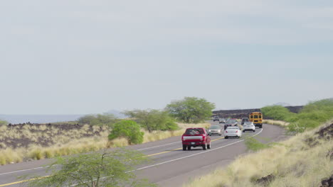 Yellow-American-School-Bus-Driving-On-Hawaii-Kamehameha-Highway-Road-On-Cloudy-Day,-4K