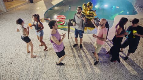 Friends dancing and enjoying a vibrant pool party at night