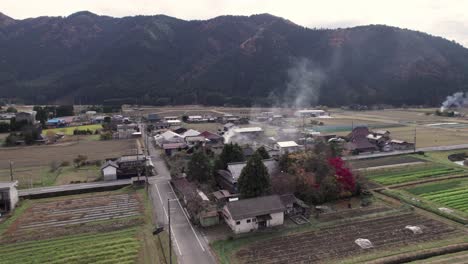 drone establishing fly rural farmland agricultural fields of keihoku japan roads and houses with mountain background