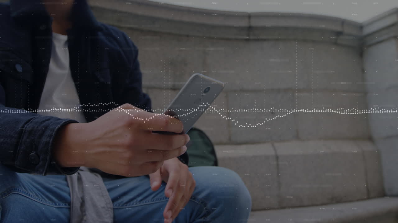 Animation of multiple graphs over low angle view of biracial man sitting and using smartphone