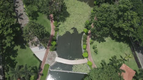 aerial view of modern urban park featuring lakes, lush gardens, bridges, green space, pathways and trees