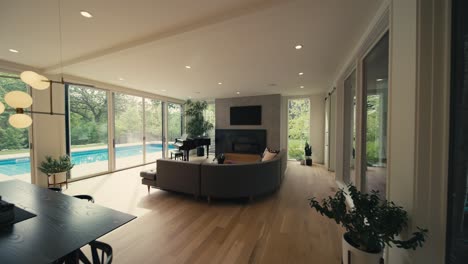 wide push in shot of the interior of a luxury home showing a dining table modern couch fireplace and a grand piano next to large windows