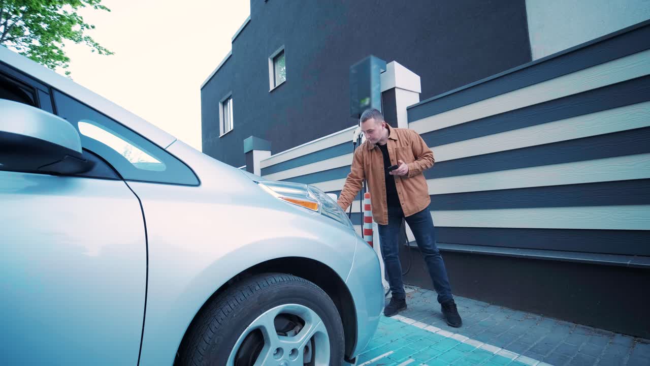 Processo di rifornimento di un'auto elettrica. Inquadratura sotto lo sportello in cui si ricarica l'auto elettrica ecologica. Lo sportello di ricarica dell'auto elettrica si apre automaticamente. Una mano maschile inserisce un'auto erettile