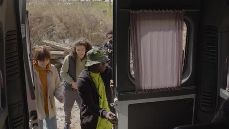 coworkers production taking material for a recording from a van while other worker setting up a camera in the street