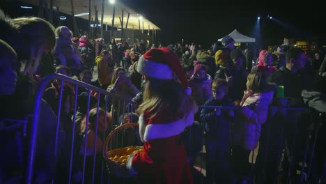 one santaclaus woman give tangerine as gift for kids at christmas