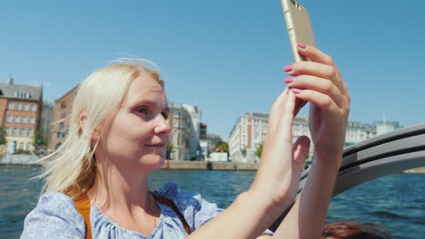 a woman takes pictures of herself against the background of copenhagen's city line sails on a sights