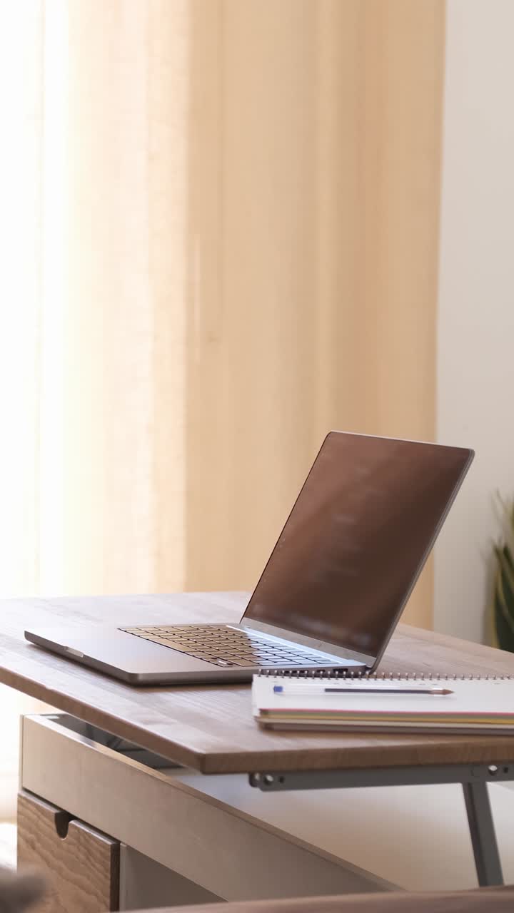 Happy woman writing in diary while working on laptop at home