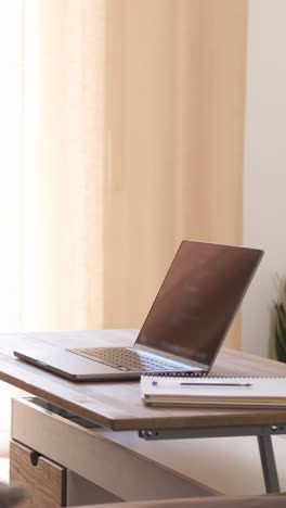 Happy woman writing in diary while working on laptop at home