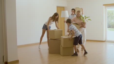 happy family bringing cardboard boxes with things into new house