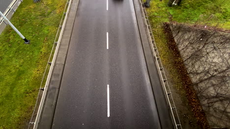 trucks and cars driving on a road while a car changing from right lane to the left lane on a black asphalt in gdynia