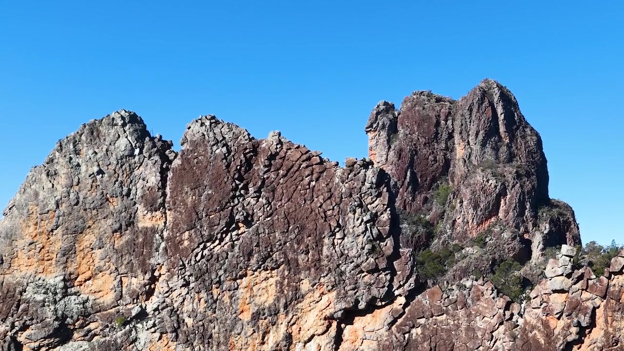 Zoom lento su antiche cime vulcaniche e scogliere frastagliate sotto un cielo azzurro limpido