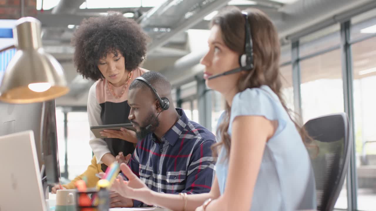 Happy diverse businesspeople discussing over a computer at an office