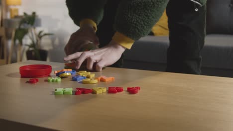 persona que limpia un juguete en forma de letra de color en la mesa en casa para un niño diagnosticado con tea o dislexia 1