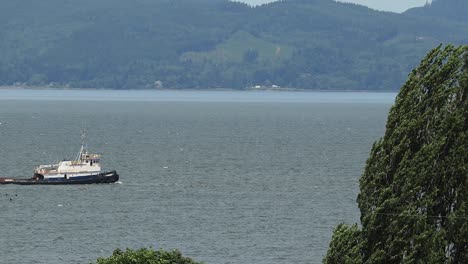 Remolcador-Tirando-De-Una-Barcaza-De-Sal-En-El-Río-Columbia-En-Junio-Con-El-Estado-De-Washington-En-El-Fondo-Desde-Las-Costas-De-Oregon