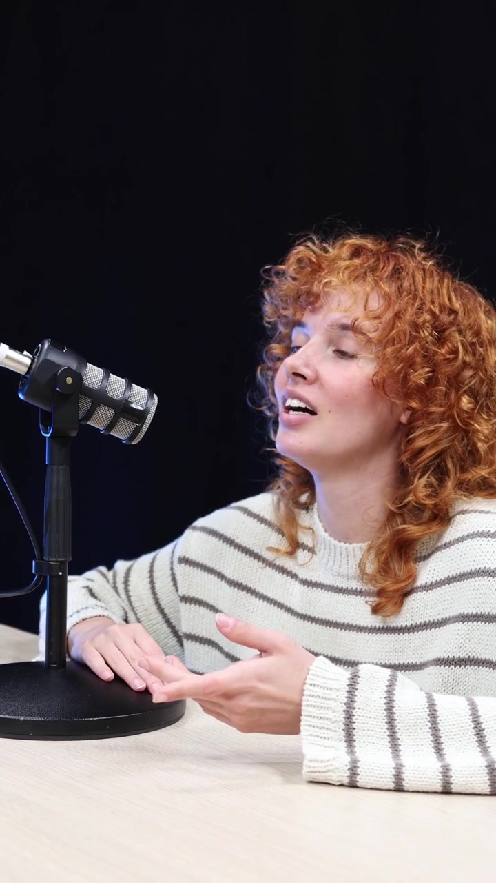 Young Woman Speaking and Gesturing into a Microphone for a Podcast