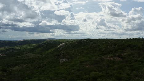 Dolly-in-aerial-drone-shot-of-the-beautiful-green-and-rocky-countryside-of-Sítio-Novo,-Brazil-in-the-state-of-Rio-Grande-do-Norte-with-farmland-surrounding-below