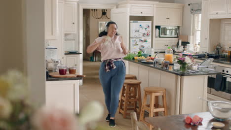 una adolescente con sobrepeso feliz bailando en la cocina divirtiéndose celebrando el fin de semana realizando movimientos de baile divertidos escuchando música usando auriculares